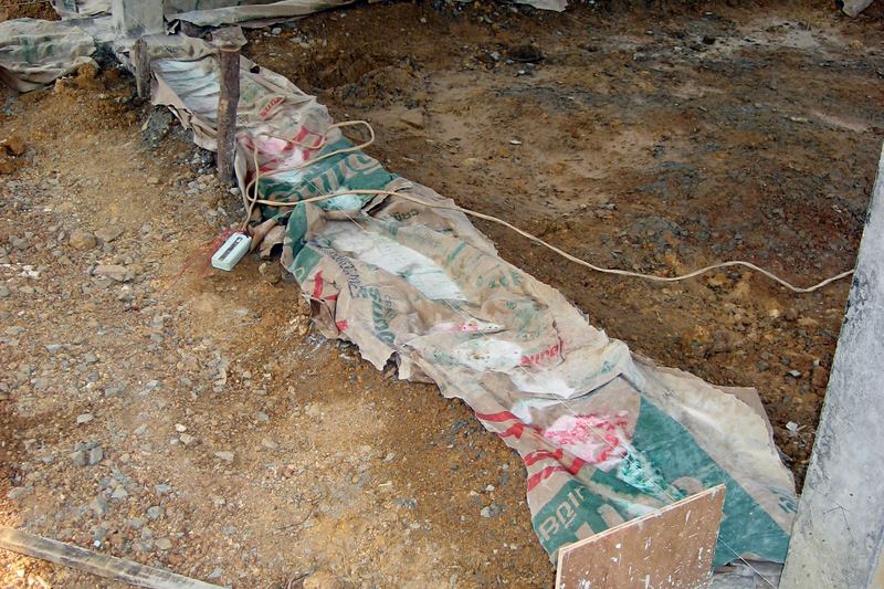 A footing covered with sacks after pour to let the concrete cure. Location: Trat Province, Thailand.